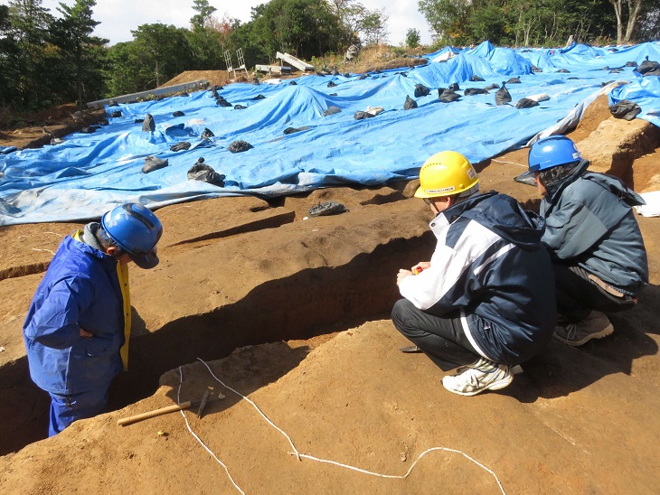 発掘現場で竪穴住居について検討している様子